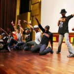 Dançarinos de hip hop iraquianos e Michael Parks Masterson (ajoelhado, à extrema direita) em um acampamento de 10 dias para aspirantes a artistas e intérpretes iraquianos na Academia Nacional de Artes Cênicas e Visuais da Unidade, no Iraque, em 2007 .