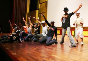 Dançarinos de hip hop iraquianos e Michael Parks Masterson (ajoelhado, à extrema direita) em um acampamento de 10 dias para aspirantes a artistas e intérpretes iraquianos na Academia Nacional de Artes Cênicas e Visuais da Unidade, no Iraque, em 2007 .
